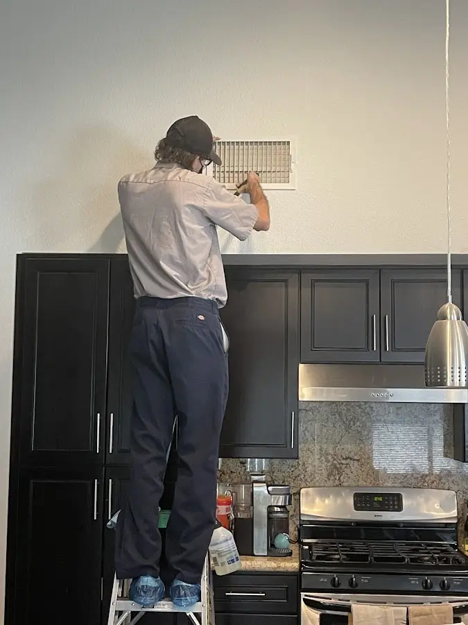 Technician inspecting an air vent during HVAC service in Little Rock